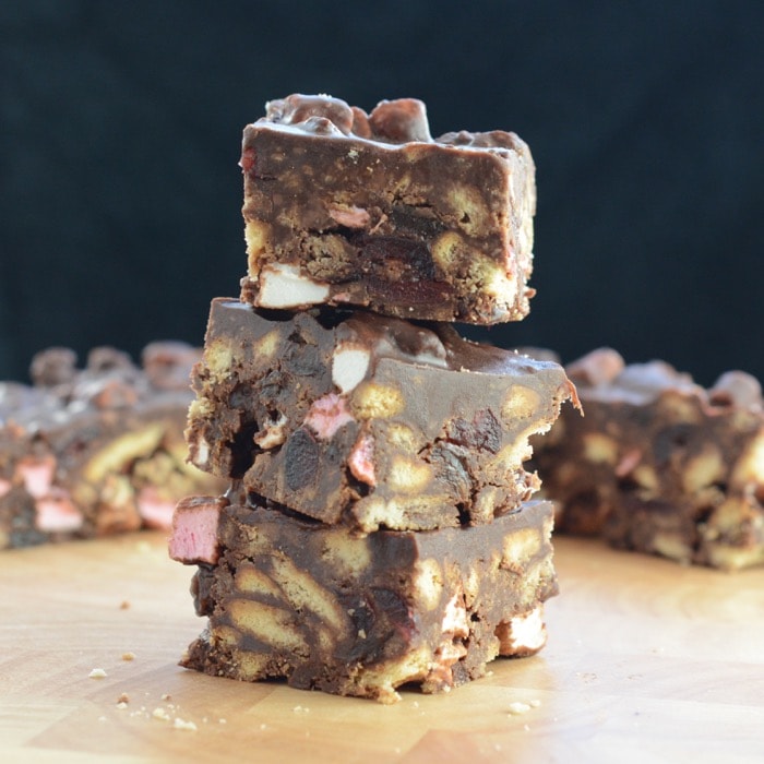 Three cut squares of rocky road piled haphazardly on top of one another in a stack. 