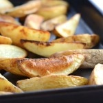 Homemade potato wedges in a baking tray.