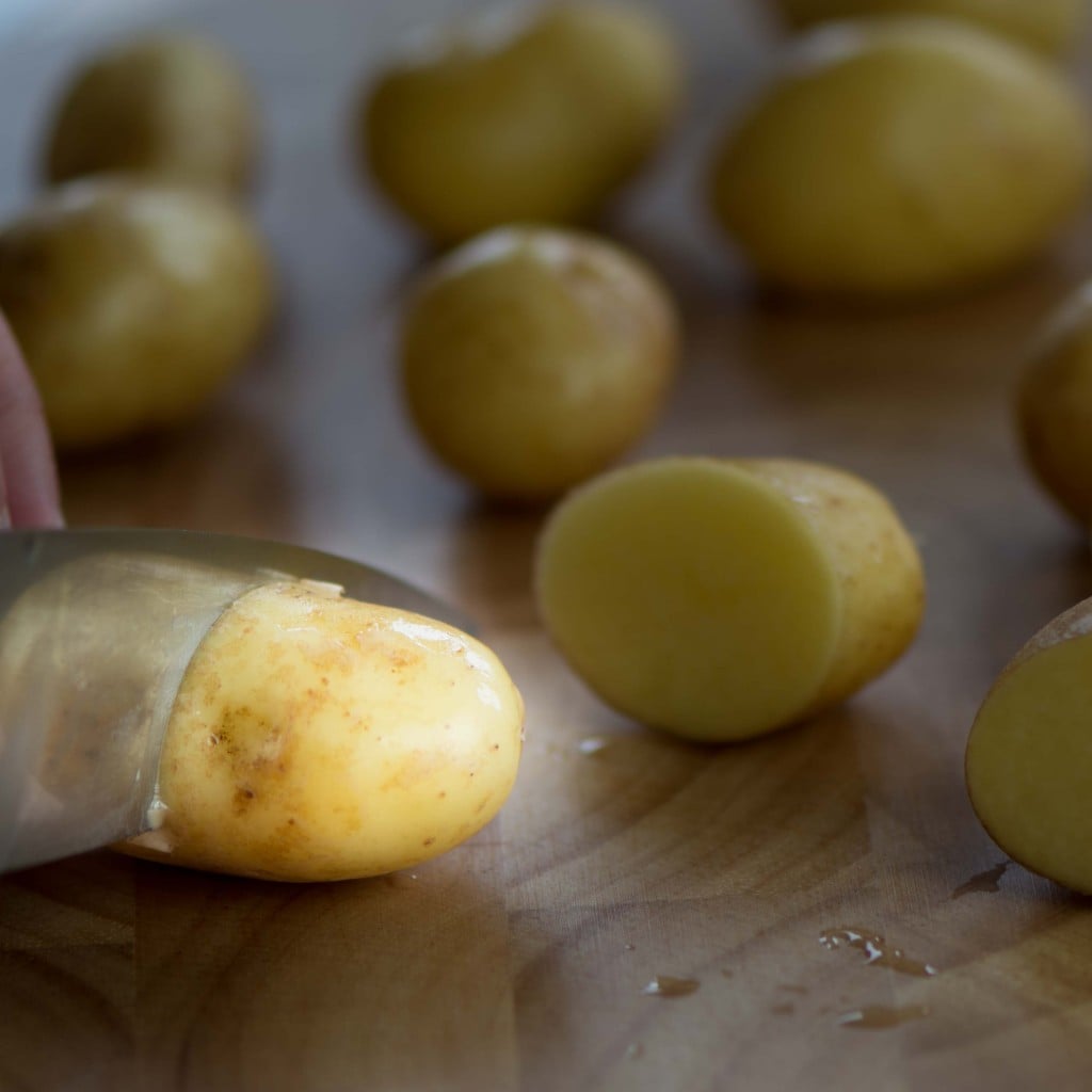 A new potato being sliced with a sharp knife.