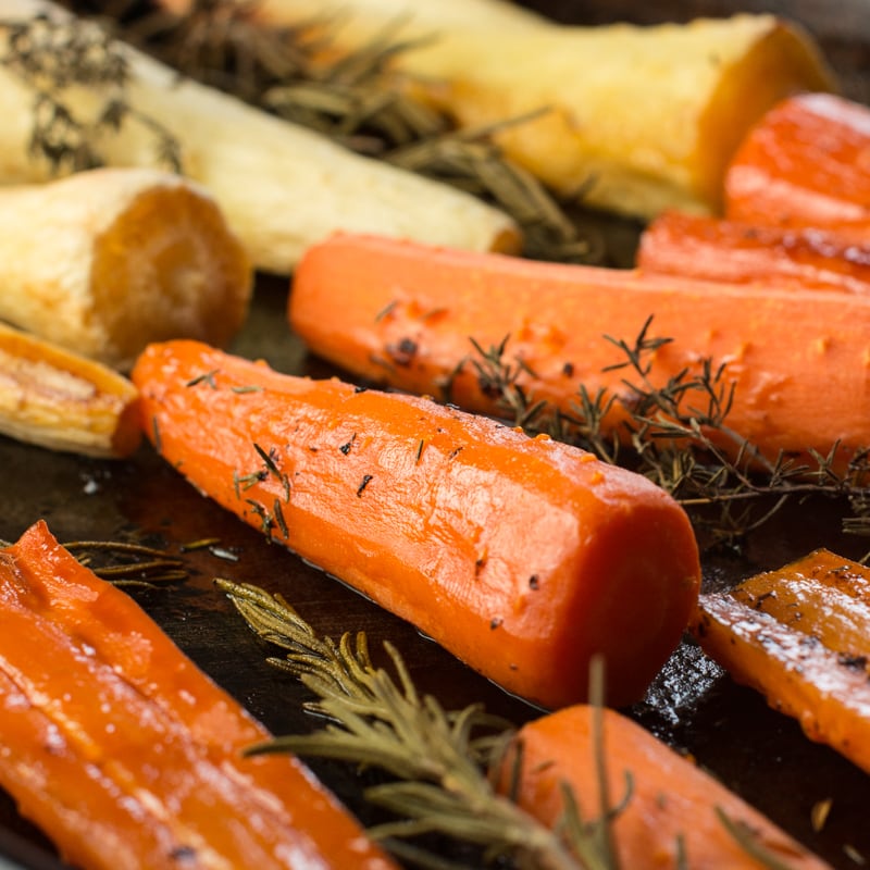 Cooked honey roasted carrots and parsnips zoomed in and focussed on a carrot. 