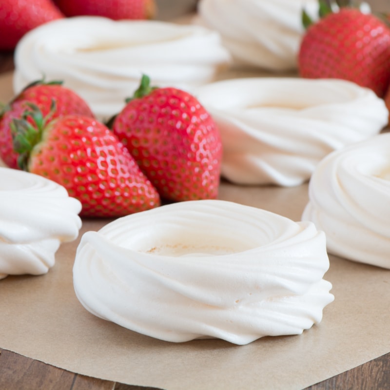 Piped meringue nests surrounded by fresh strawberries.