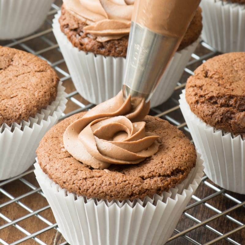 Nutella buttercream being piped onto a Nutella cupcake.
