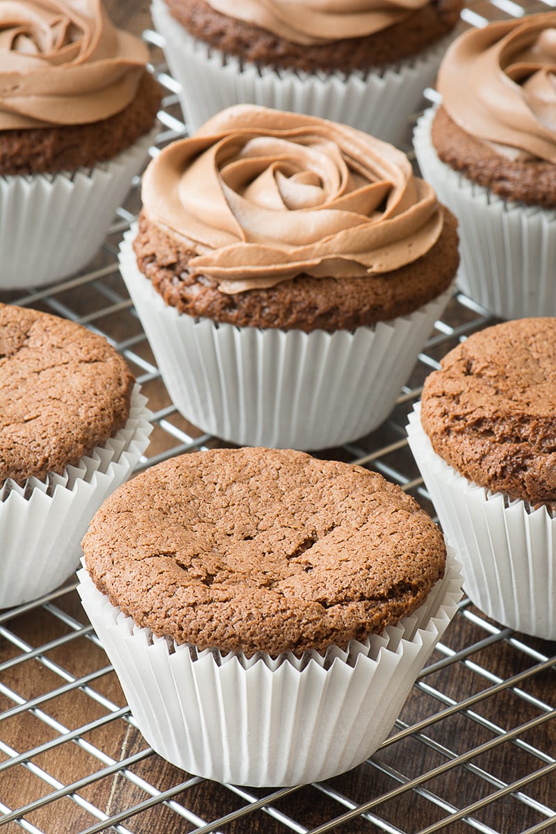 A plain Nutella cupcake on a cooling rack with some iced cupcakes in the background.