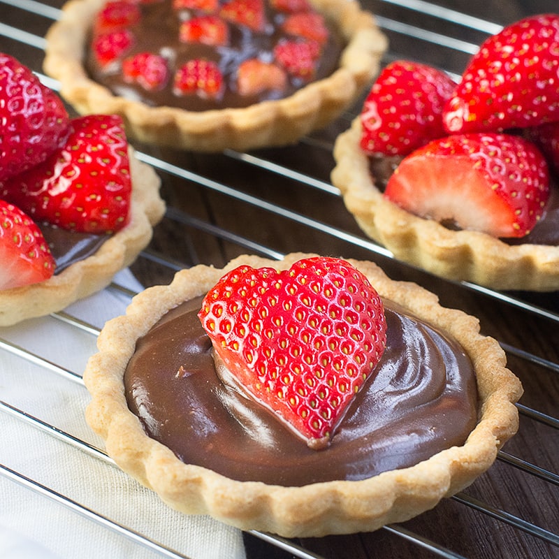 Treat someone you love with these strawberry and champagne truffle tarts - a sweet shortcrust pastry tart filled with rich milk chocolate and champagne ganache and topped with champagne soaked strawberries.