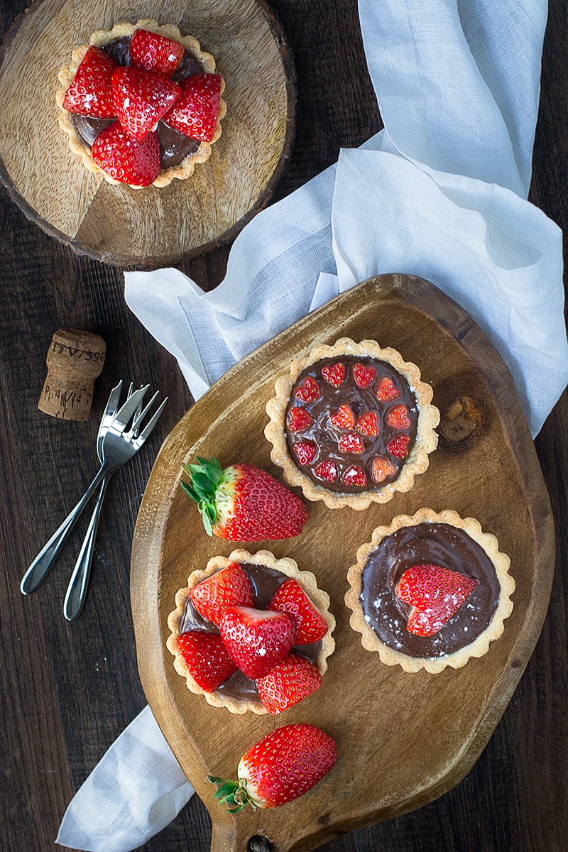 Treat someone you love with these strawberry and champagne truffle tarts - a sweet shortcrust pastry tart filled with rich milk chocolate and champagne ganache and topped with champagne soaked strawberries.