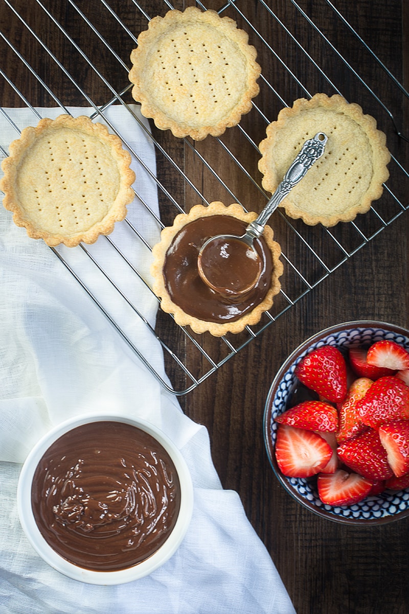 Treat someone you love with these strawberry and champagne truffle tarts - a sweet shortcrust pastry tart filled with rich milk chocolate and champagne ganache and topped with champagne soaked strawberries.
