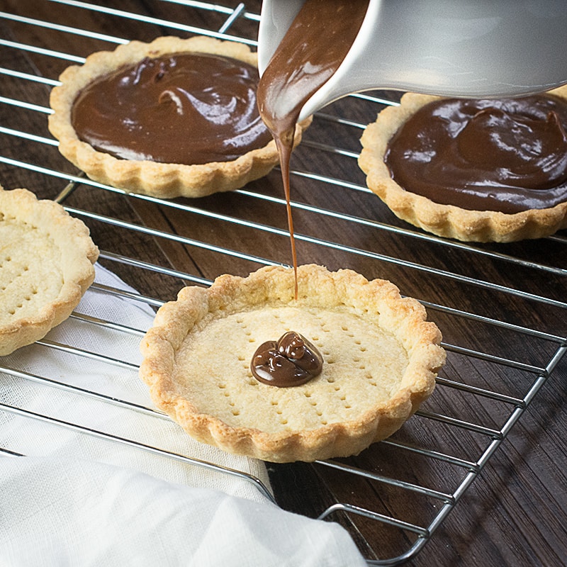 Treat someone you love with these strawberry and champagne truffle tarts - a sweet shortcrust pastry tart filled with rich milk chocolate and champagne ganache and topped with champagne soaked strawberries.