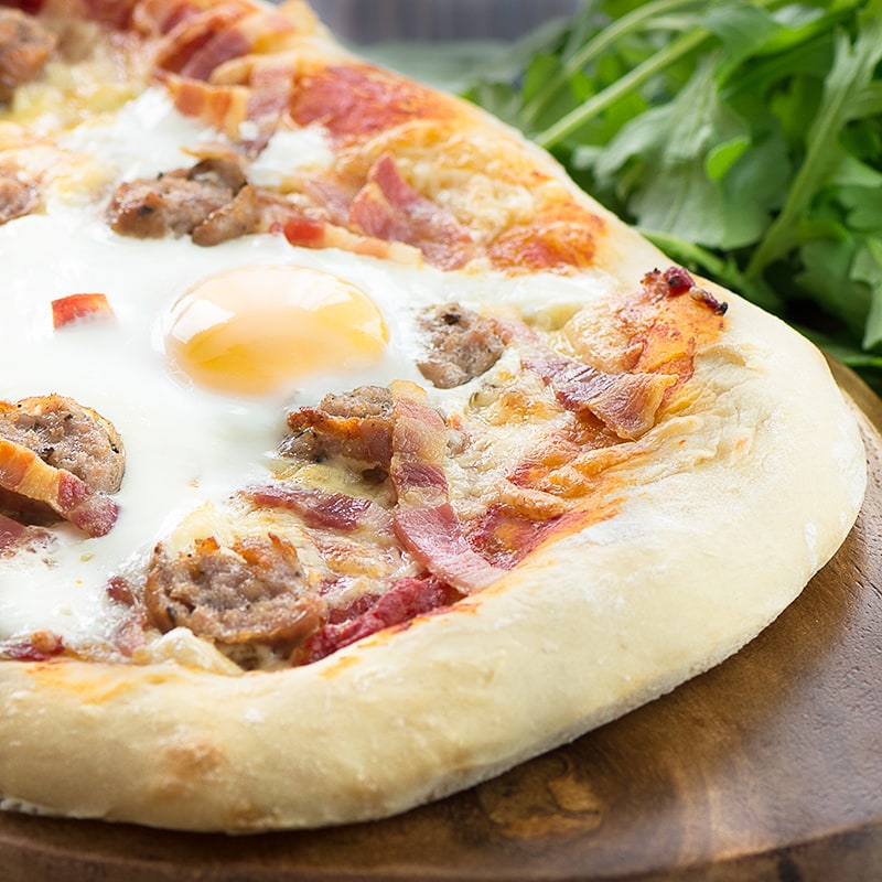 All-day breakfast pizza - delicious homemade pizza dough topped with sausage, bacon, cheese and even a "fried" egg.