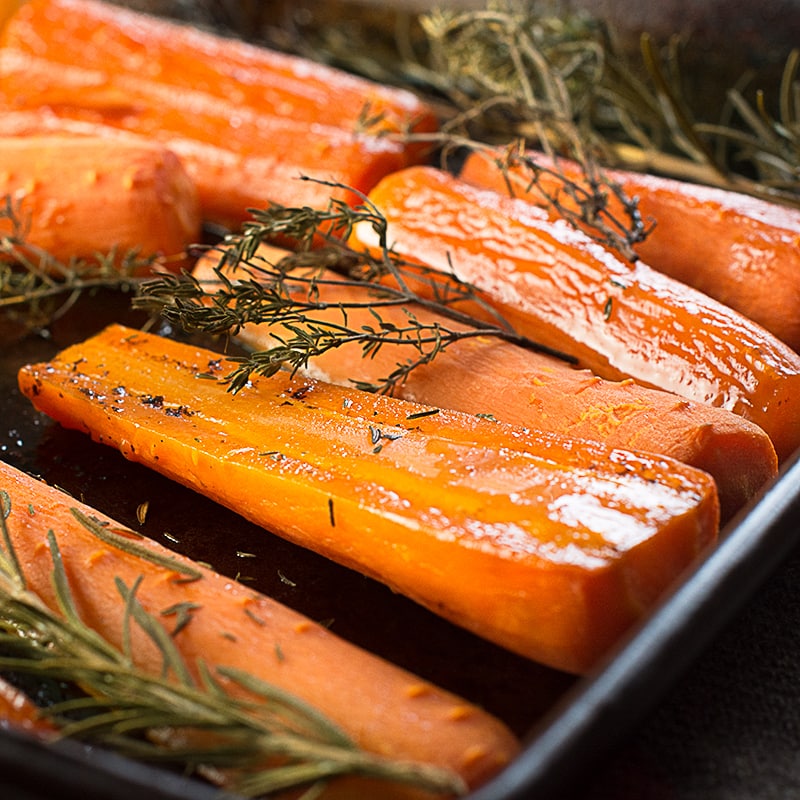 Raw carrots on their baking tray glazed with honey and ready to bake. 
