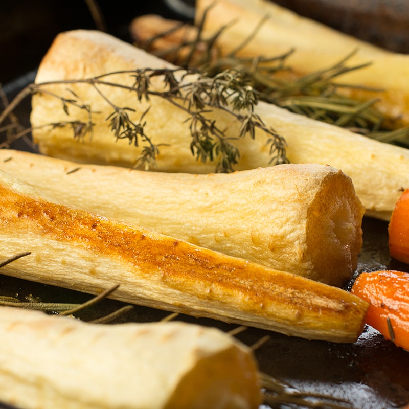 Cooked parsnips on their baking tray glazed with honey and ready to serve. 