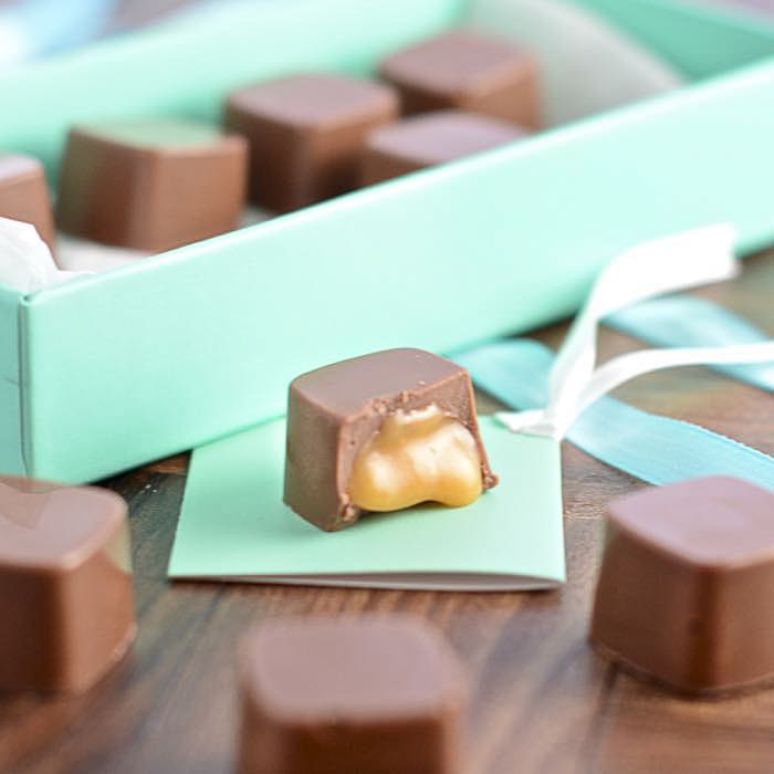 Closeup of squeezing filling of salted caramel cream from confectionery bag  into candy molds for preparing handmade chocolate pralines Stock Photo -  Alamy