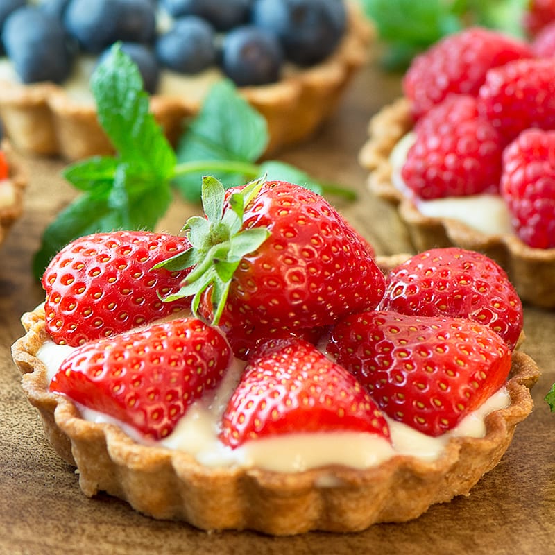 Summer berry and custard tarts - crispy pastry filled with creamy vanilla custard and topped with fresh, juicy berries. A delicious, elegant summer dessert.