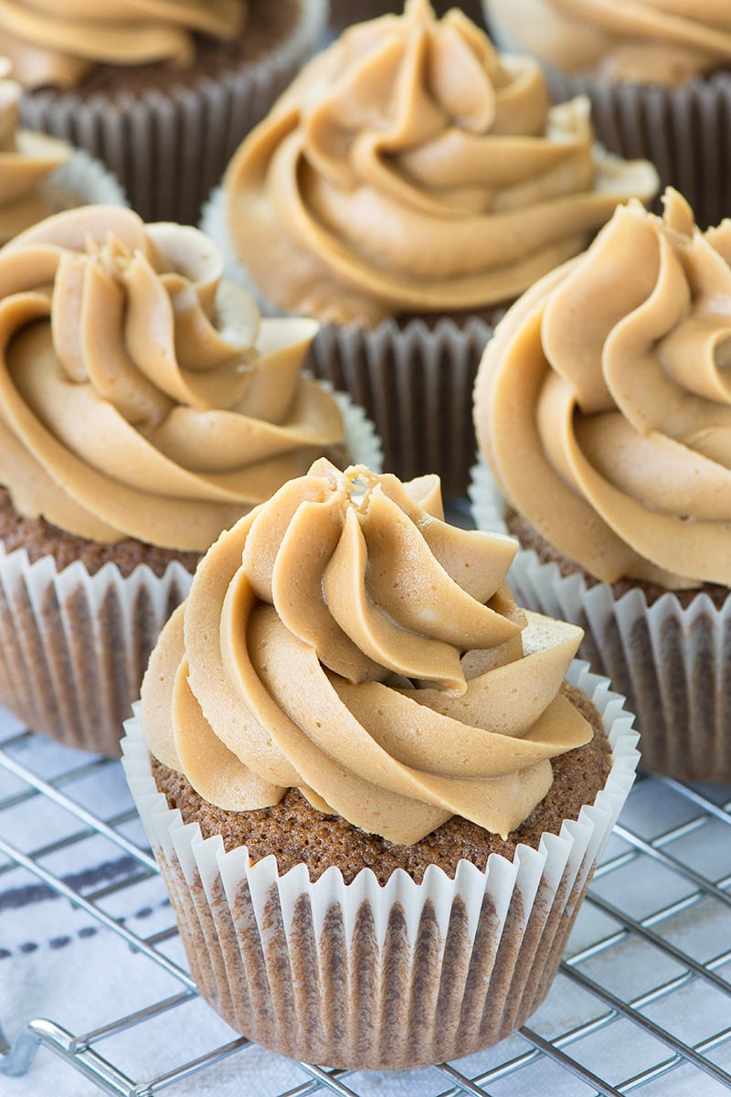 Coffee cupcakes topped with coffee buttercream on a cooling rack.