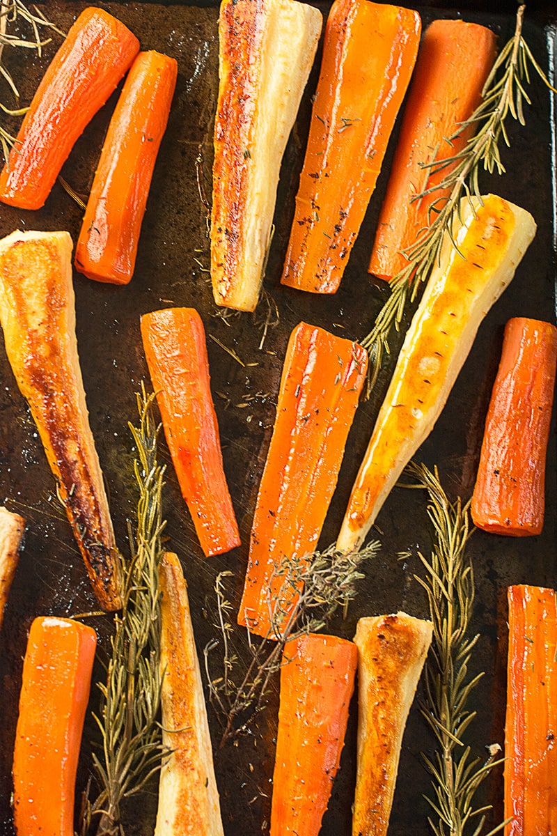 Cooked honey roasted carrots and parsnips on their baking tray shown from above. 