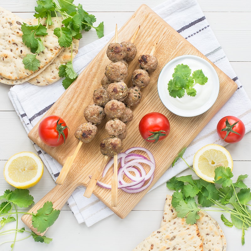 These easy lamb koftas flavoured with spices, mint and lemon zest are perfect for a summer barbecue, served in a flat bread with salad and yogurt.