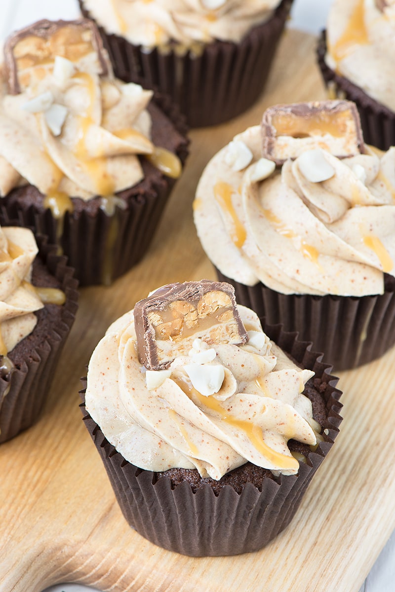 Snickers Cupcakes - Chocolate Cupcakes filled with caramel sauce and topped with smooth peanut buttercream, more caramel, crunchy peanuts and a little slice of Snickers.