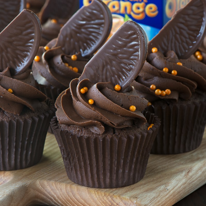 Chocolate orane cupcakes topped with buttercream, chocolate orange and orange sprinkles with a Chocolate Orange in the background.