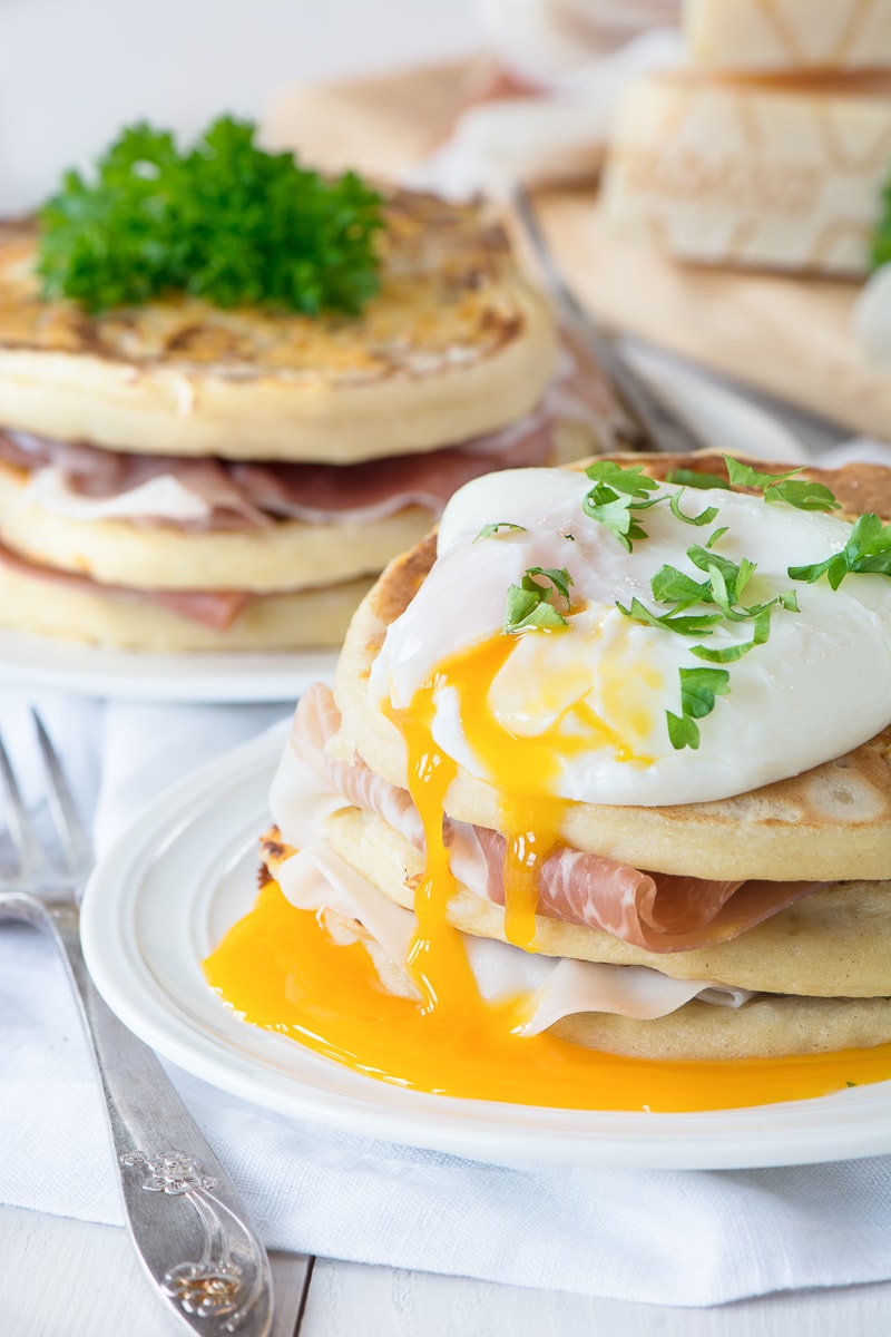 Two stacks of Grana Padano pancakes, one toped with a packed egg. Layered with Prosciutto di San Daniele.
