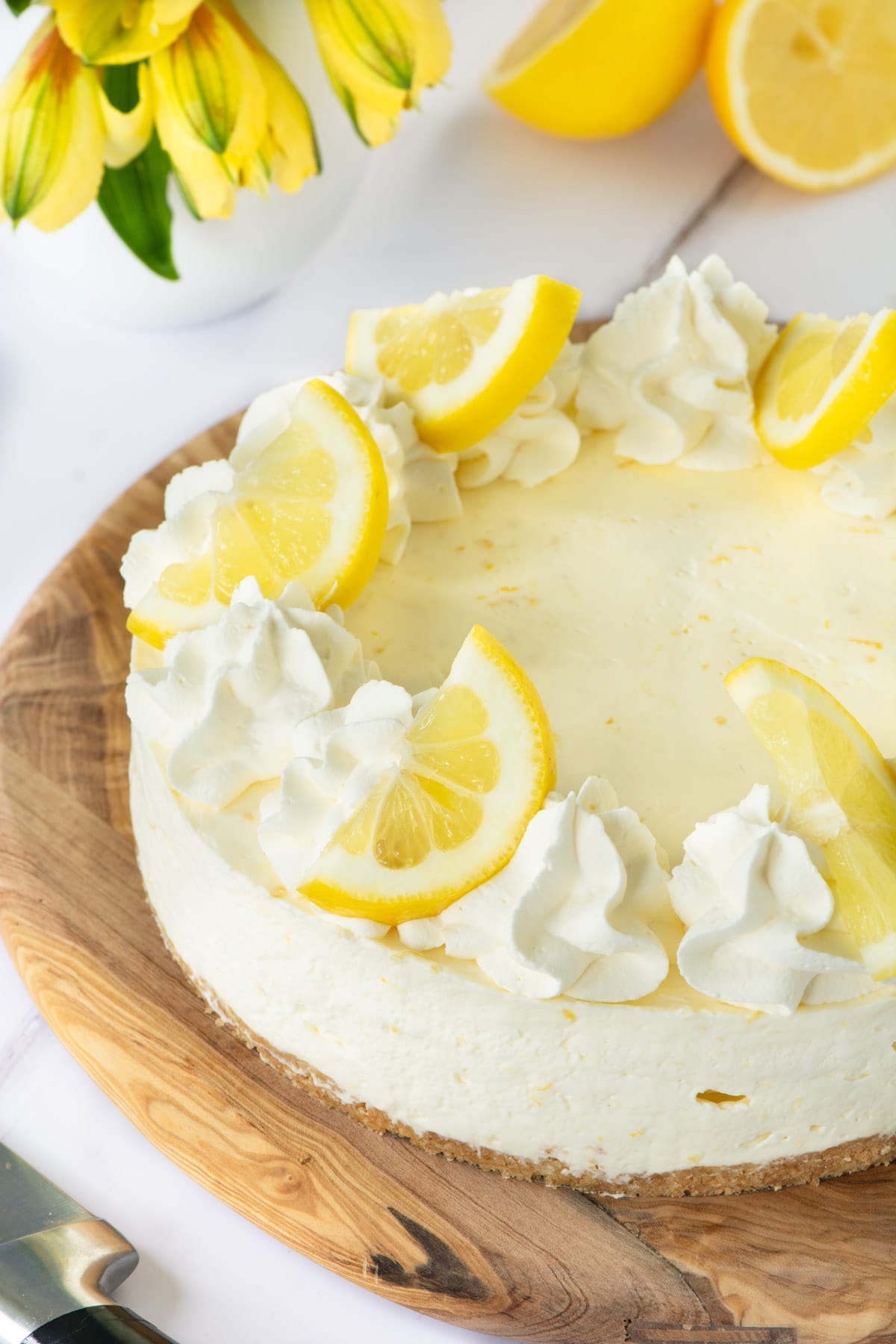 Lemon cheesecake topped with whipped cream and lemon slices.