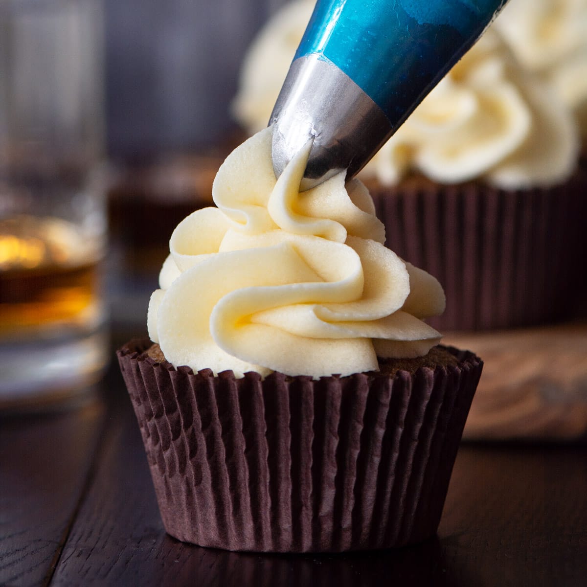 Whiskey buttercream being piped onto a coffee cupcake.