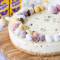 White chocolate mini egg cheesecake. topped with mini eggs. There's a boxes of mini eggs in the background.