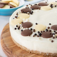 No bake white chocolate cheesecake decorated with white and milk chocolate buttons and chocolate sprinkles.