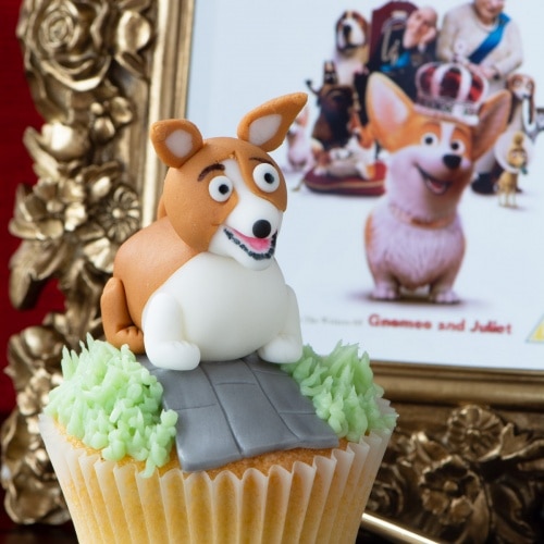 A fondant corgi cupcake with The Queen Corgi DVD cover in the background