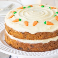 Carrot cake topped with cream cheese buttercream and decorated with sugar carrots.