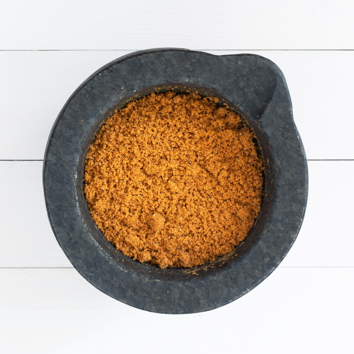 Finely ground Lotus Biscoff Biscuits in a mortar (stone grinding bowl)