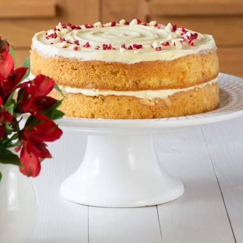 A white chocolate cake on a cake stand.