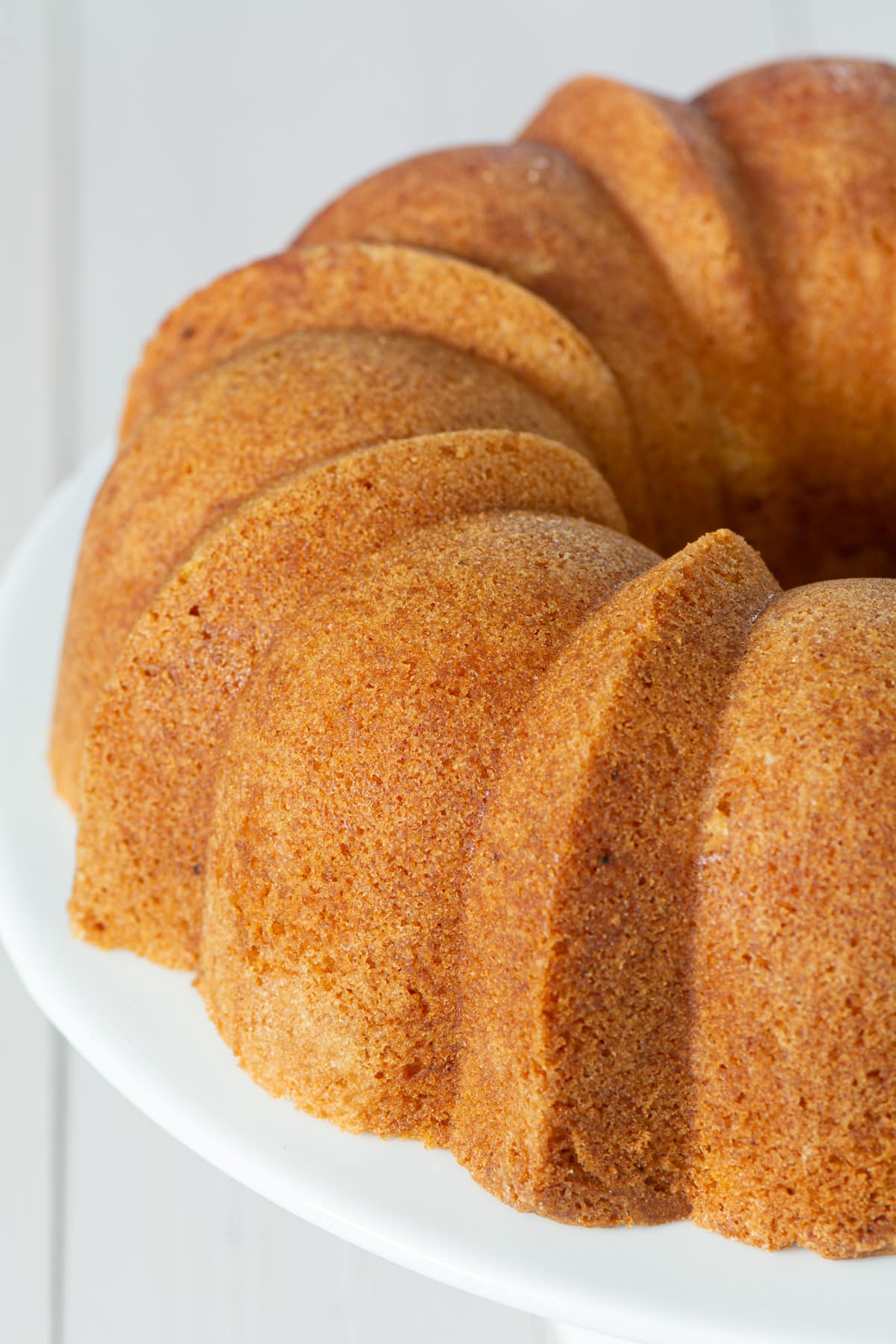 A plain vanilla bundt cake on a cake stand.