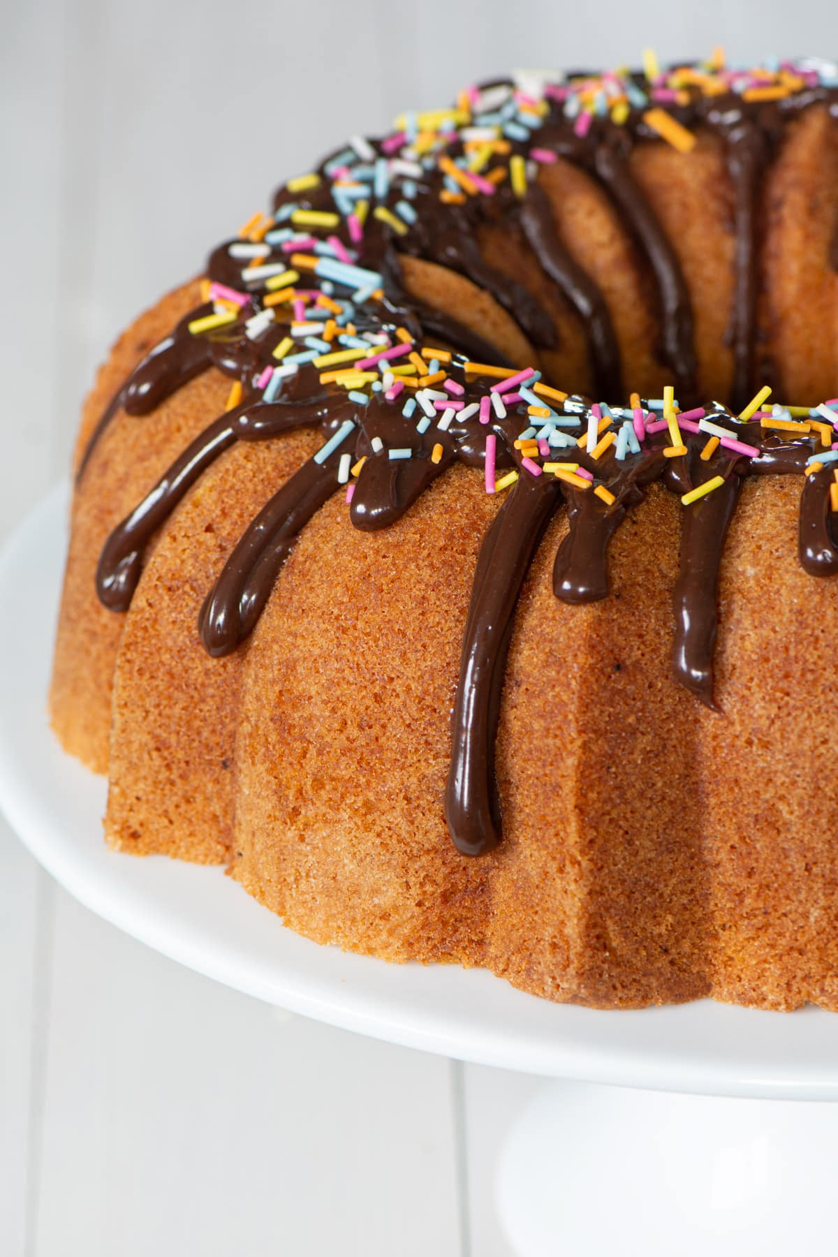 Bundt cake topped with ganache and sprinkles.