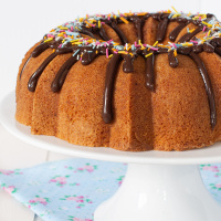 Vanilla bundt cake on a white cake stand.