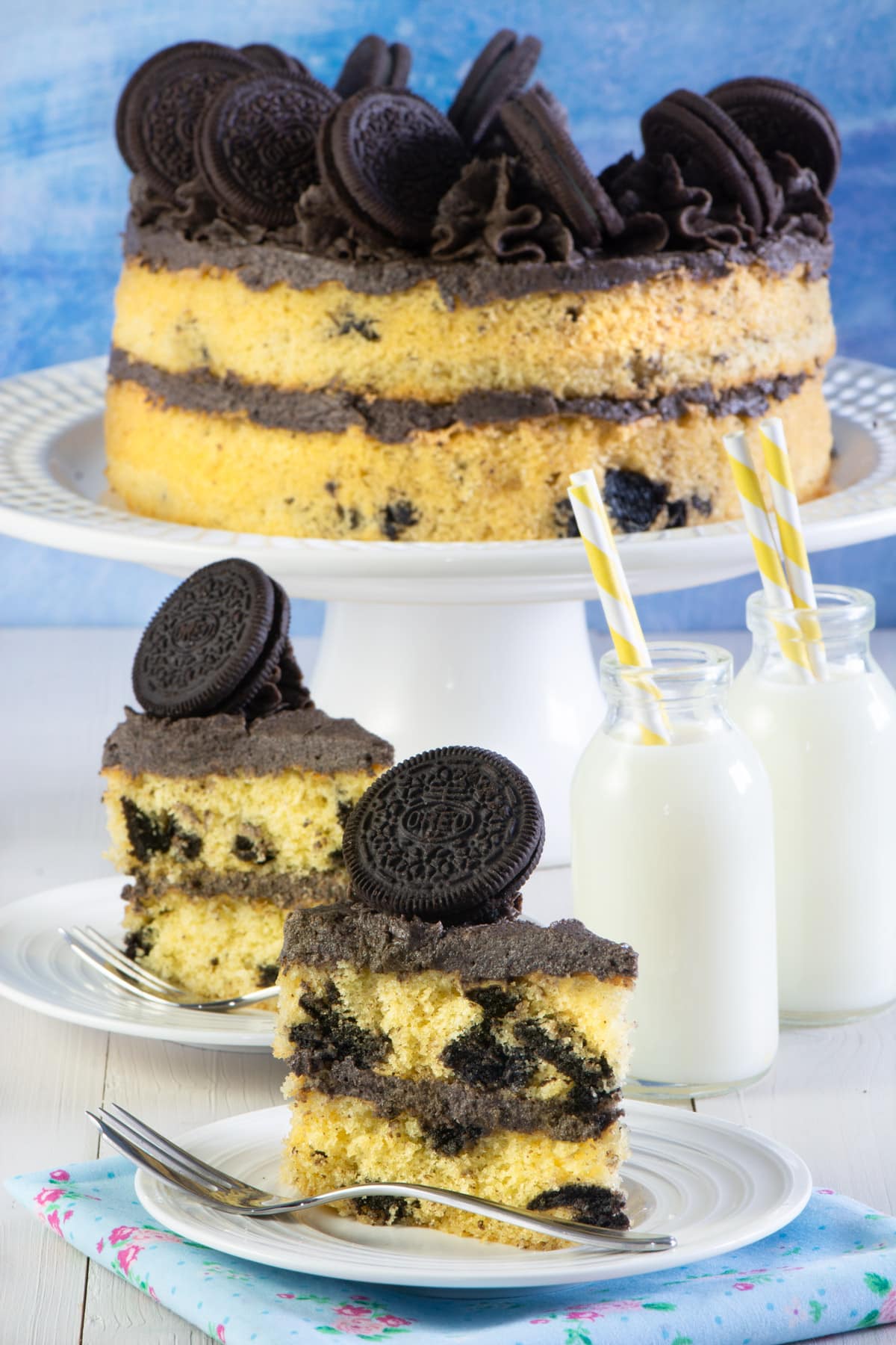 Oreo cake on a stand with 2 slices on plates. 