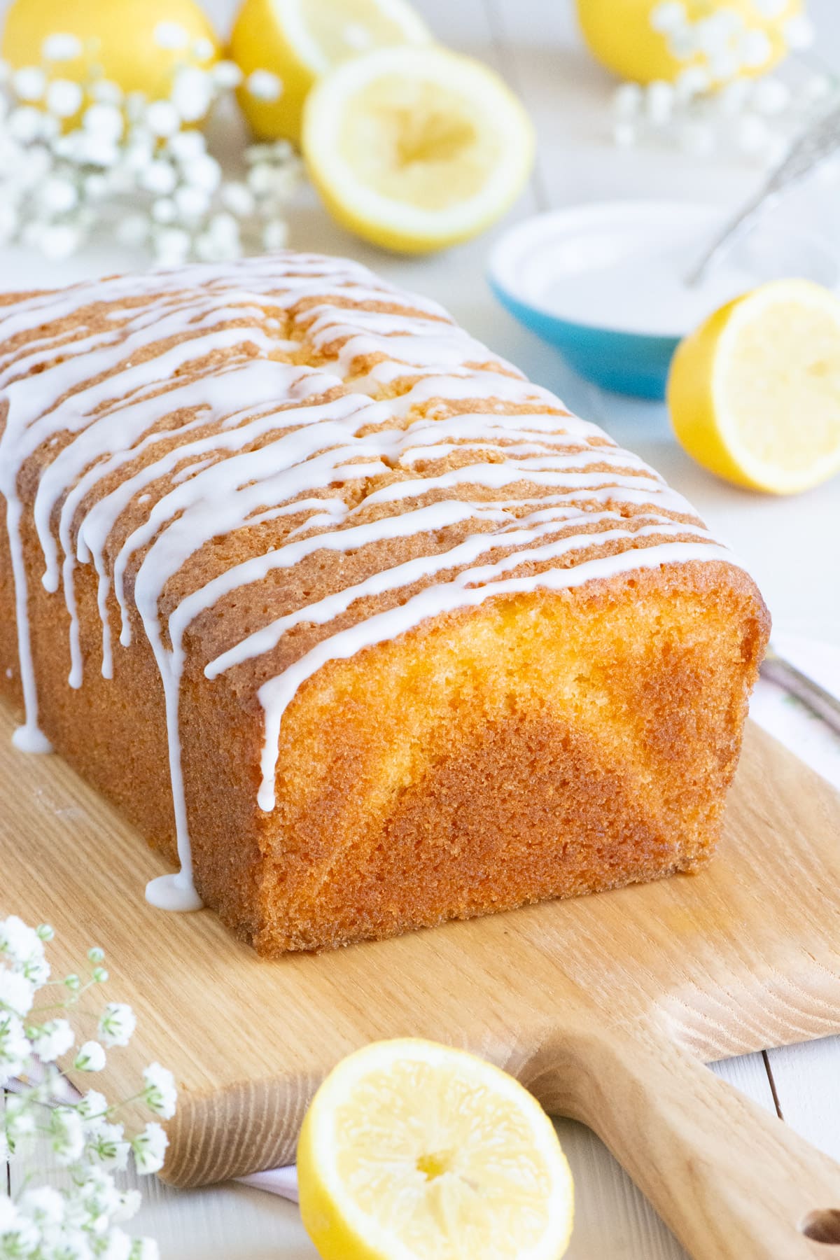 Unsliced lemon cake with drizzled lemon icing seen from the unsliced end. 