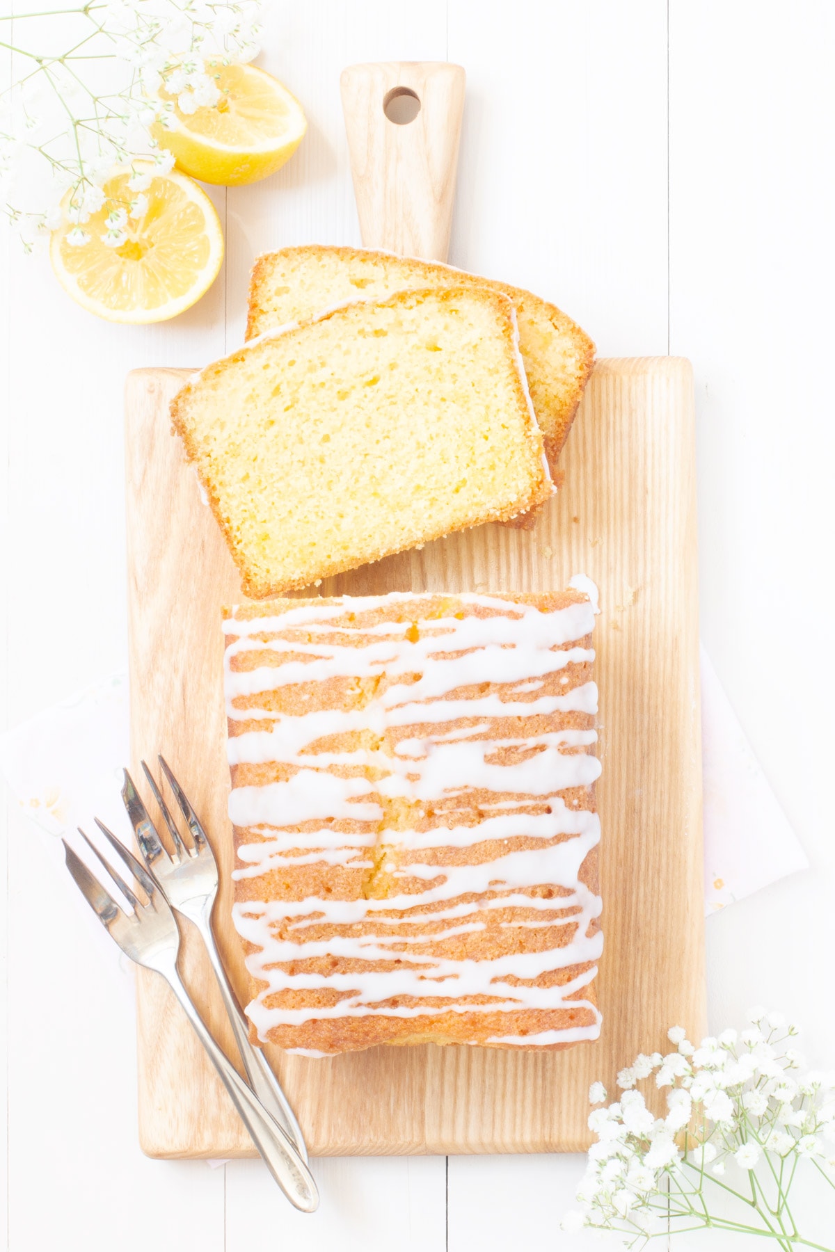 Lemon drizzle cake viewed from above with two slices at one end placed one on top of each other. 