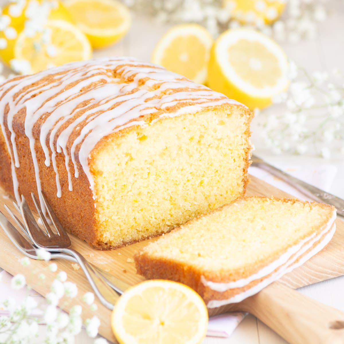 Lemon drizzle cake seen at eye level with one slice at the front of the shot and the inner crumb visible. 