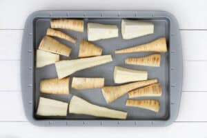 Chopped parsnips in a baking tray ready to be roasted